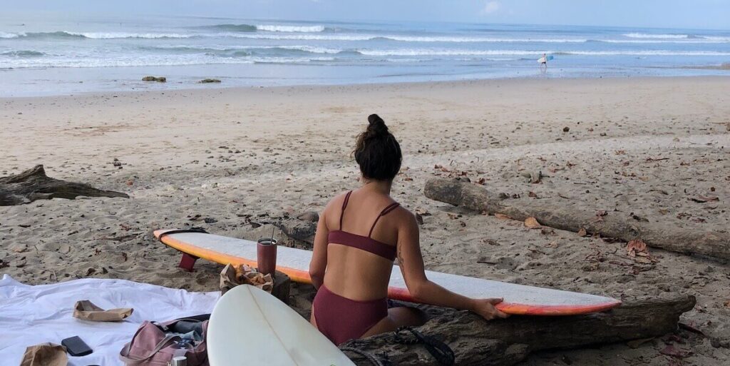 Surferin wachst ihr Longboard am Strand